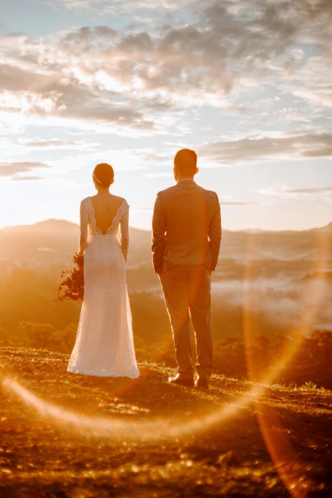 couple de futurs mariés de dos face au coucher de soleil sur les montagnes